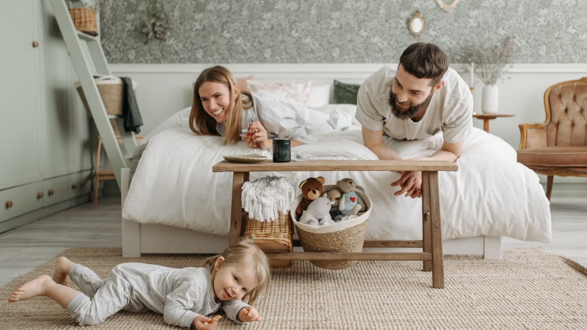 A joyful family bonding in a cozy bedroom, featuring a playful child and loving parents.
